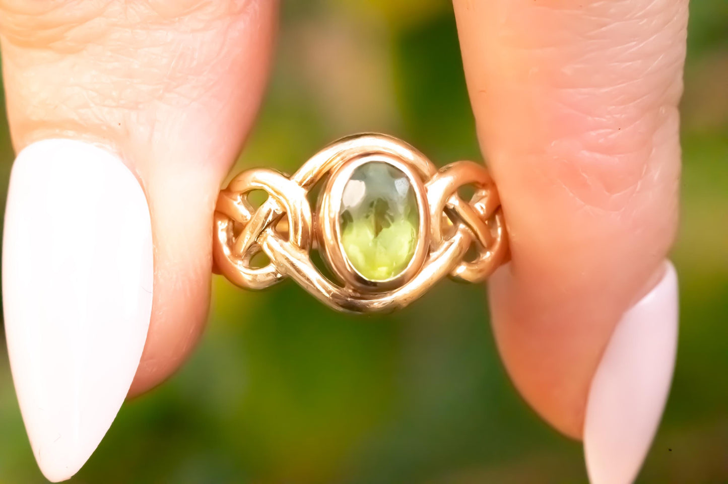 pretty peridot Celtic ring, shown in hand - bright stone with rare Clogau Welsh gold in 9ct yellow and rose gold.